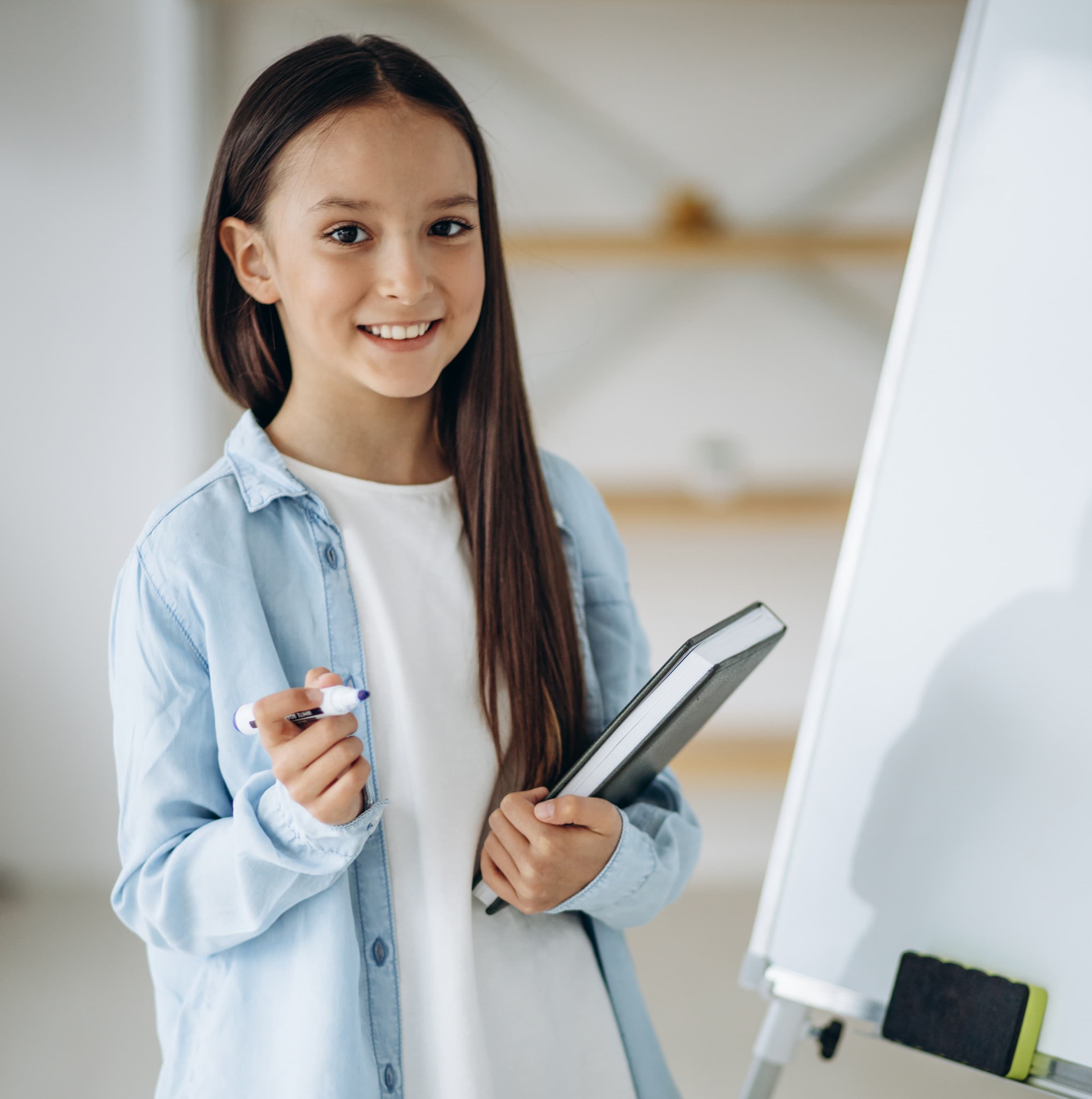 Élève du primaire écrivant au tableau blanc devant sa classe